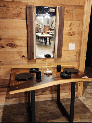 Wooden dining table with black chairs against a wooden wall.